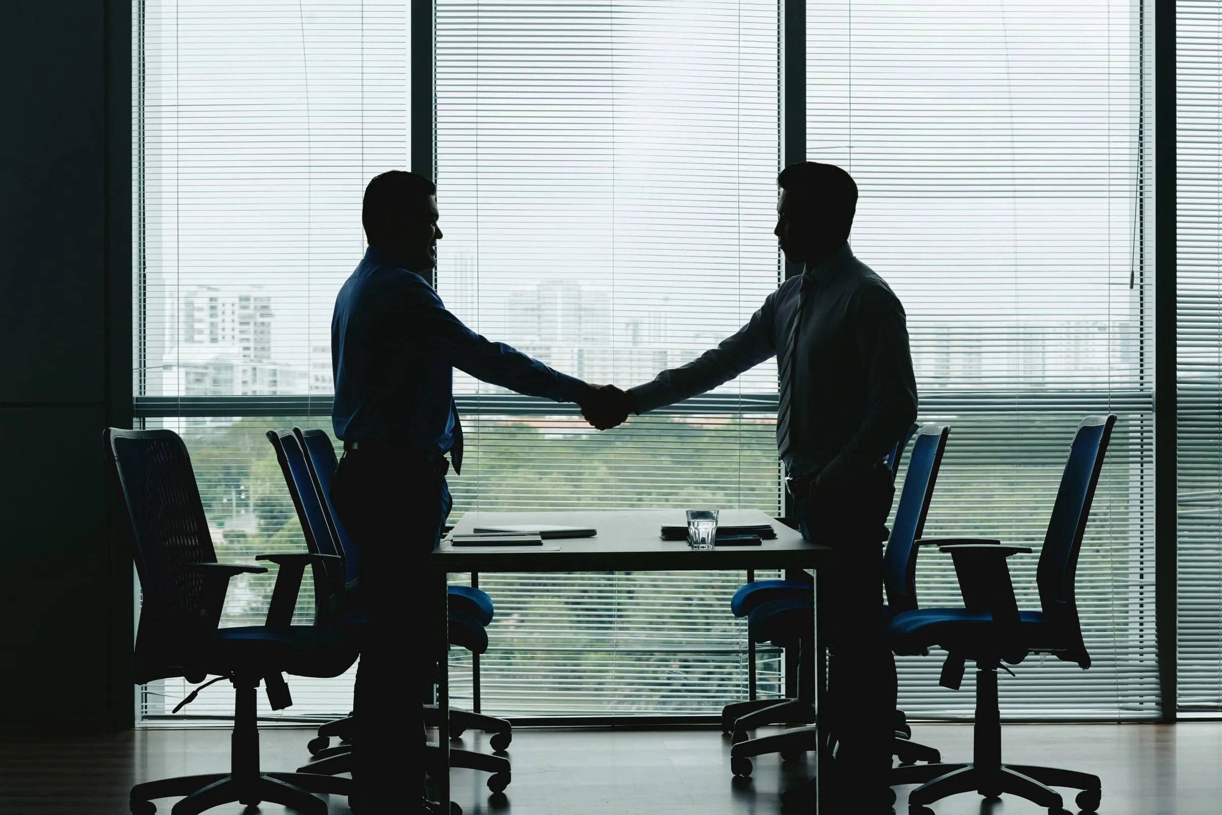 Two people shaking hands in a meeting room