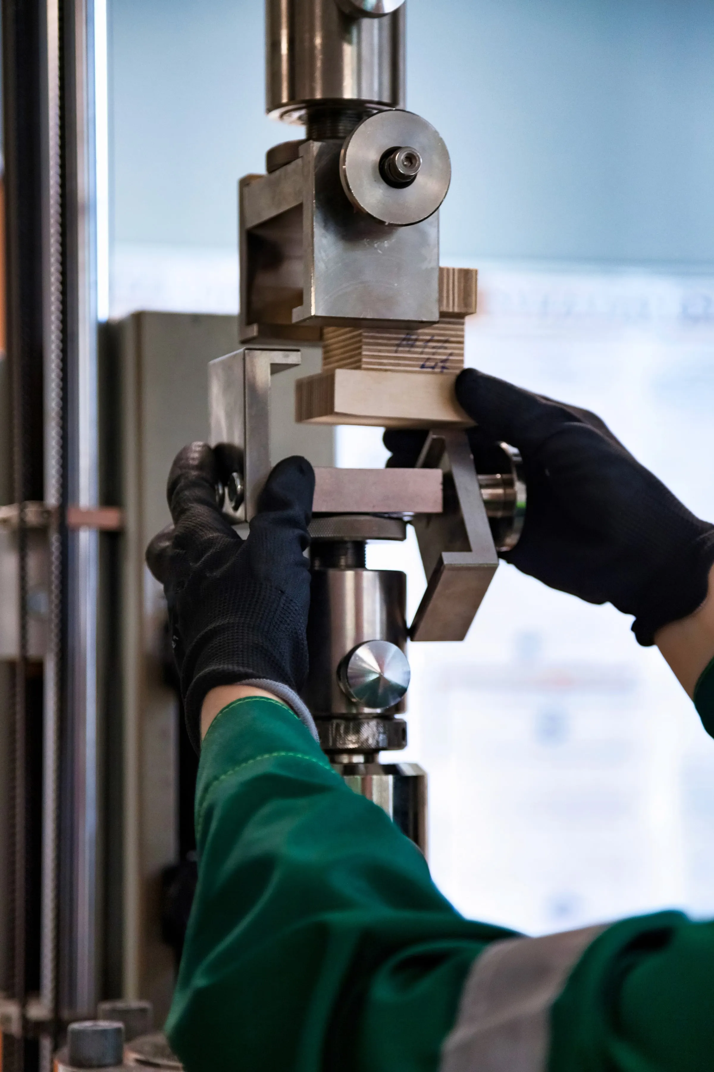 Operator's gloved hands setting a part in a machine