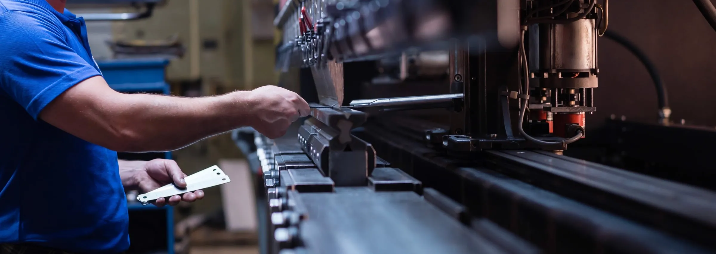 Operator loading sheet metal into a CNC press brake